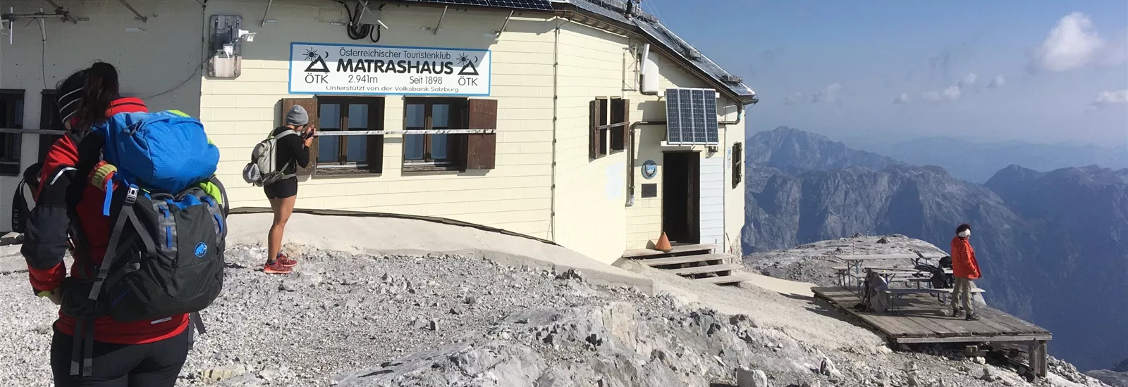 Gipfelfoto vom Matrashaus auf dem Hochkönig bei gutem sonnigen Wetter. Mehrere Wanderer sind von hinten zu sehen, wie diese aufbrechen.