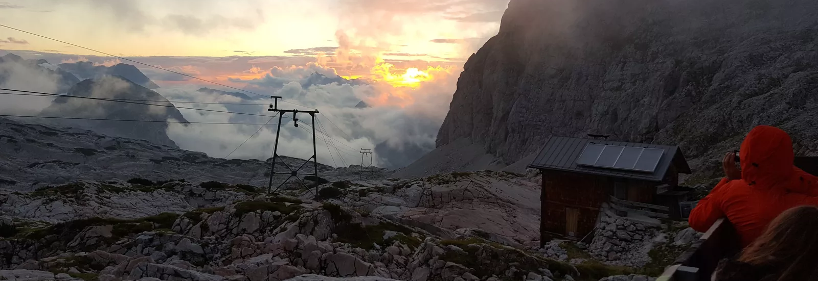 Sonnenuntergang über den Alpen mit Berghütte und Felsplateau nach einer Bergwanderung.